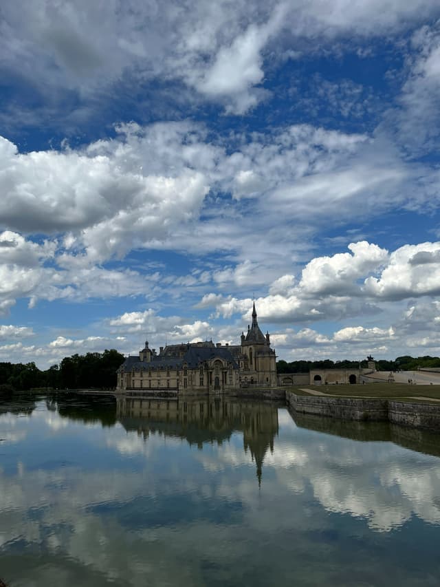 Le château de Chantilly pris en photo avec l'iPhone 13 : les nuages dans le ciel comme les reflets dans l'eau sont parfaitement restitués
